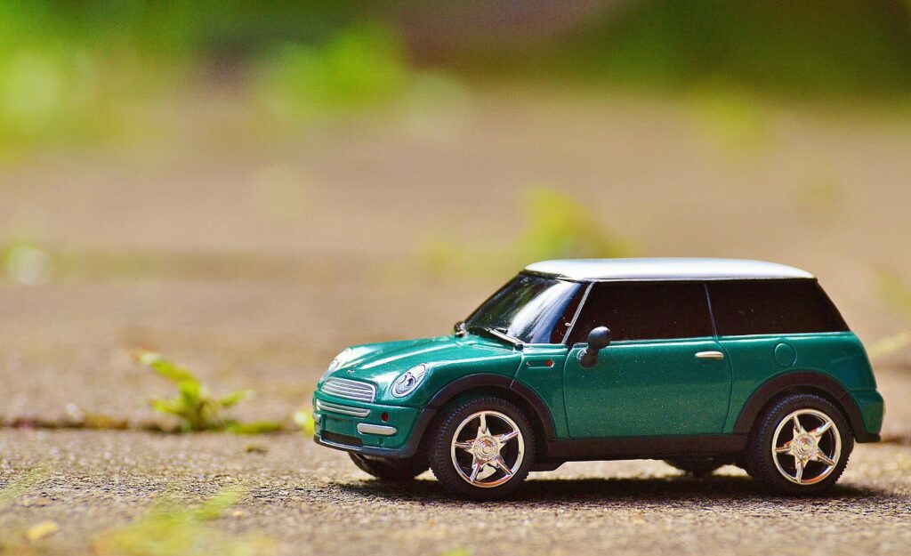 mini cooper auto model vehicle 35967 Green toy Mini Cooper car on pavement featuring a shallow depth of field outdoors.