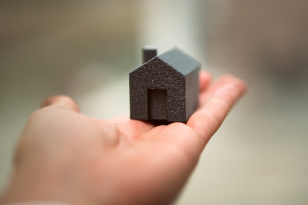 pexels photo 29091316 Close-up of a hand holding a miniature house model representing real estate concepts like buying or investment.