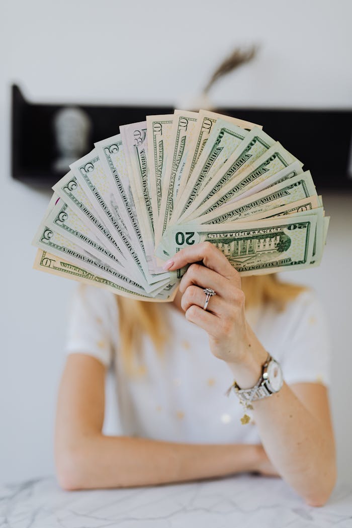 who-we-are A person holding a fan of US dollar bills, symbolizing wealth and financial success.