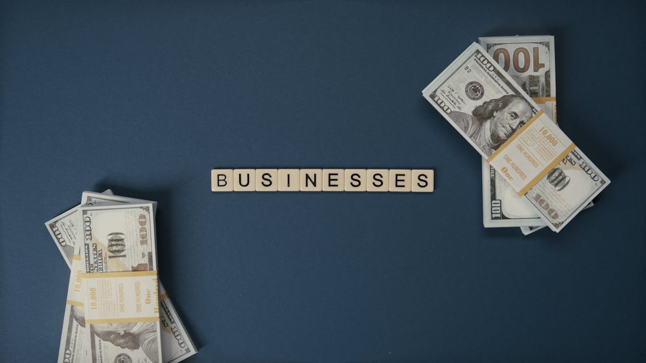 why-choose-us Top view of dollar bills and 'businesses' letter tiles symbolizing financial success.